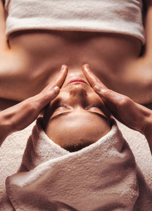 Massage du visage d'une femme ayant une serviette sur la tête