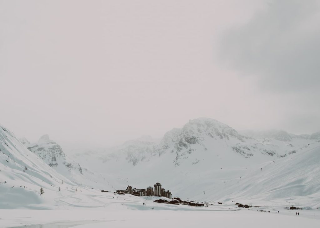 Station de ski de Tignes Val Claret enneigée au milieu des montagnes dans les Alpes et face au lac recouvert de neige